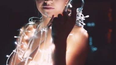 Kız ya da genç bir kadın bir Noel ağacını çelenkle süslüyor.