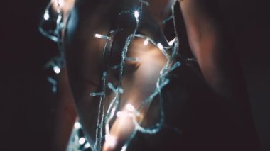 Kız ya da genç bir kadın bir Noel ağacını çelenkle süslüyor.