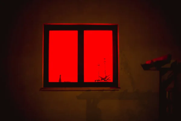Czerwone światło z okna. Czerwone okno mistycznie świeci w nocy. — Zdjęcie stockowe