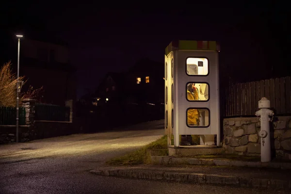 Ragazza parla nella cabina telefonica notturna. telefono stradale mistico e misterioso Immagine Stock