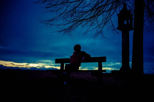 Gizemli bir hacker silueti, bankta oturan yalnız, isimsiz bir adam. 