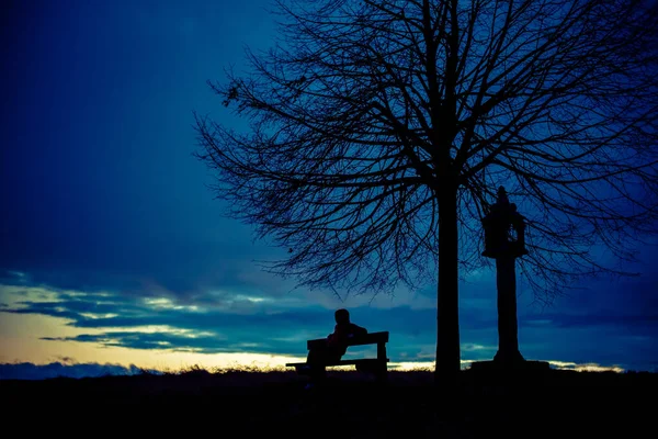 Gizemli bir hacker silueti, bankta oturan yalnız, isimsiz bir adam. 