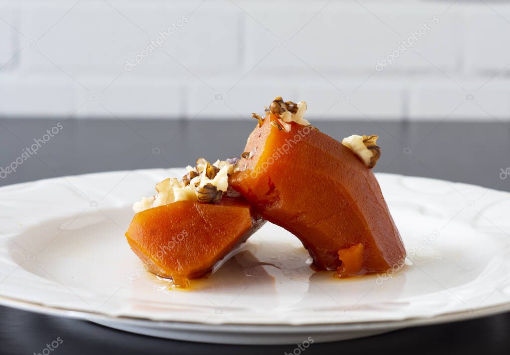 Pumpkin dessert with walnut sprinkles cooked with steamed sugar, on a white plate macro