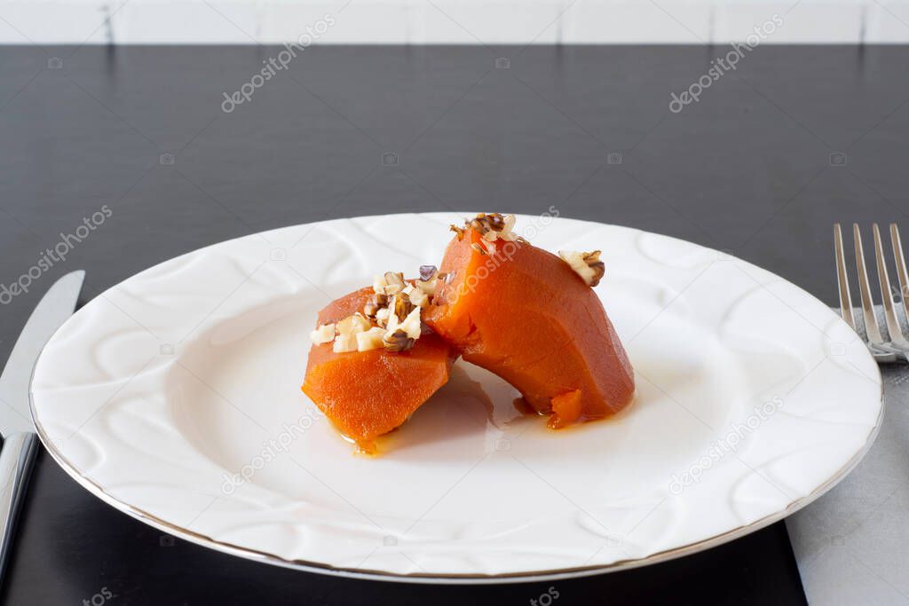 Pumpkin dessert with walnut sprinkles cooked with steamed sugar, top view on a white plate .