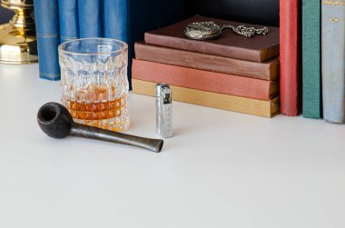 Eski kütüphane piposu, çakmak, cep saati, kitaplar ve viski. Sherlock Holmes ofis masası