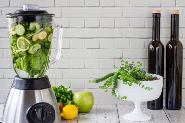 Mutfak blendırında yeşil meyve püresi hazırlama süreci. Sağlıklı yemek için yeşil smoothie. Beyaz duvarın önünde.