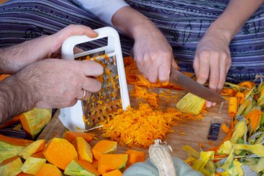 Tatlı kabaklı börek yapıyorum. Bir kadın evdeki mutfakta yerde otururken balkabağını kesiyor ve kesiyor..