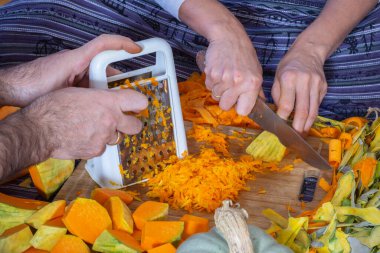 Tatlı kabaklı börek yapıyorum. Bir kadın evdeki mutfakta yerde otururken balkabağını kesiyor ve kesiyor..