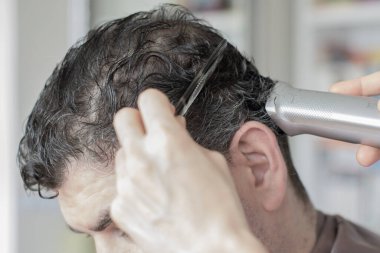 Genç kadın salgın sırasında evde kocasının saçını kesiyor. Evde kal.