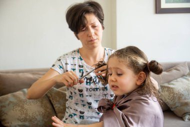 Genç bir kadın salgın sırasında kızının saçını evde kesiyor. Evde kal..