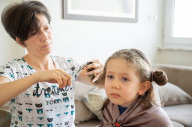 Genç bir kadın salgın sırasında kızının saçını evde kesiyor. Evde kal..