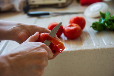 Kadın taze domatesi bıçakla soyuyor. Evli kadın taze domates ve biber doğruyor. Salata ya da yemek hazırlıyorum.