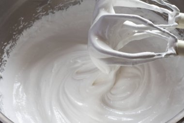 Pavlova tatlı hazırlama aşamaları. Yumurta beyazı ve şeker kırbaçlanır ve karıştırılır.