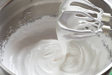 Pavlova tatlı hazırlama aşamaları. Yumurta beyazı ve şeker kırbaçlanır ve karıştırılır.