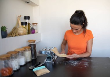 Makarna hamurunu evde makineyle açan kadın. Makarna yapmak 