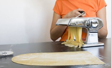 Makarna makinesinde ev yapımı fettucine hazırlıyorum. Özel ekipman, geleneksel İtalyan mutfağı konsepti, kopyalama alanı üzerine ham hamur dilimleme