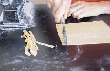 Ahşap bir mazada ev yapımı makarna hazırlıyorum. Geleneksel İtalyan mutfağı kavramı.