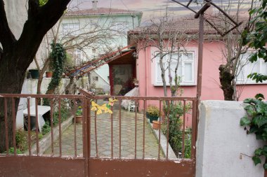 Eski pembe ev kışın son günlerinde. Ağaçlar hala kuru. İki katlı ve bahçeli..