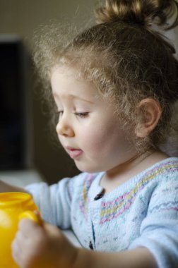 Kanat çırpan sarı saçlı tombul küçük kız oyuncaklarıyla oynuyor. seçici odak yanak ve yüz