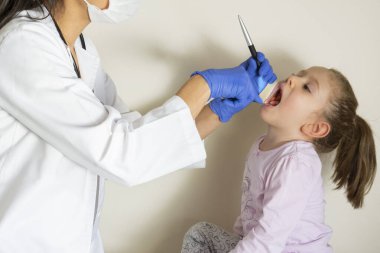 Doktoru tarafından pediatrik muayenede olan tombul küçük kız. ENT (Kulak, burun, boğaz) Muayene. Seçici Odaklanma