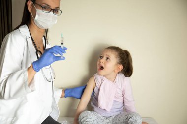 Doktoru tarafından pediatrik muayenede olan tombul küçük kız. Doktoru tarafından aşılanmış. Küçük kız endişeli ve korkmuş. Seçici Odaklanma