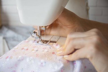 young woman sews clothes on the sewing machine. close up