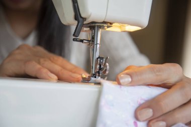 young woman sews clothes on the sewing machine. close up