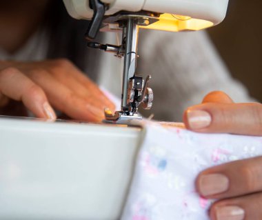 young woman sews clothes on the sewing machine. close up