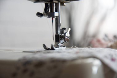 Sewing machine operation from different angles and sewing a flowered fabric. Selective Focus Machine part.