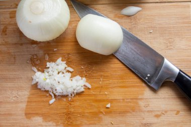 Hamburger yapmaya hazırlanırken, beyaz soğanlar şef bıçağıyla doğranır. Seçici odaklı soğan. Üst görünüm.