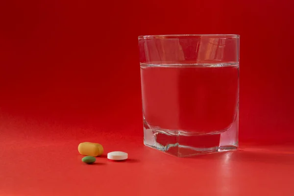 Bicchiere Acqua Medicine Pillole Droghe Isolato Sfondo Rosso — Foto Stock
