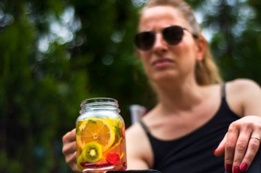 Genç kadınlar, bahçelerinde pilates ya da yoga yaptıktan sonra detoks içeceklerinin keyfini çıkarırlar..