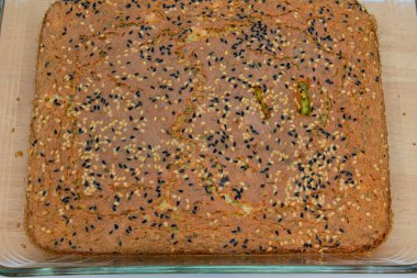 Üzerinde susam tohumu ve siyah kimyon olan dikdörtgen havuç ve tarçınlı kek..