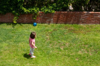 Küçük kız evlerinin bahçesindeki çimlerde frizbi oynuyor. Seçici Odaklanma Kızı.