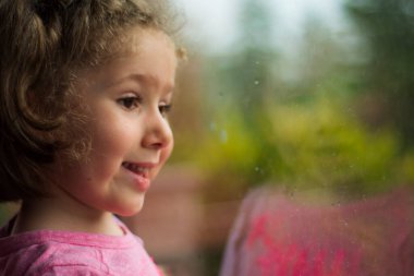 Küçük kız evinin penceresinden dışarı bakıyor. Seçici Odaklanma Kızı.