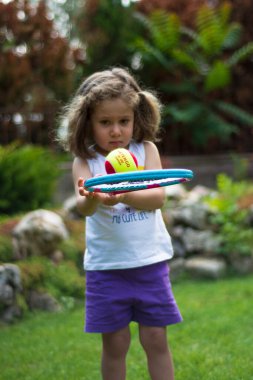 Küçük kız bir yaz günü bahçesinde tenis oynuyor. Seçici Odaklanma Kızı 