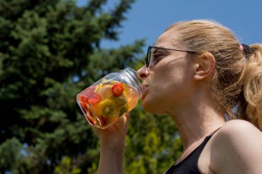 Genç kadın, bahçelerinde pilates ya da yoga yaptıktan sonra detoks içeceklerinin keyfini çıkarıyor..