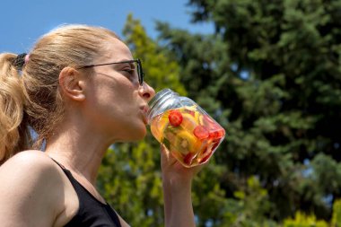 Genç kadın, bahçelerinde pilates ya da yoga yaptıktan sonra detoks içeceklerinin keyfini çıkarıyor..