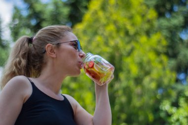 Genç kadın, bahçelerinde pilates ya da yoga yaptıktan sonra detoks içeceklerinin keyfini çıkarıyor..
