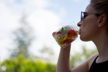 Genç kadın, bahçelerinde pilates ya da yoga yaptıktan sonra detoks içeceklerinin keyfini çıkarıyor..