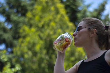 Genç kadın, bahçelerinde pilates ya da yoga yaptıktan sonra detoks içeceklerinin keyfini çıkarıyor..