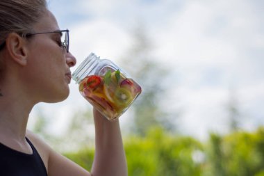 Genç kadın, bahçelerinde pilates ya da yoga yaptıktan sonra detoks içeceklerinin keyfini çıkarıyor..