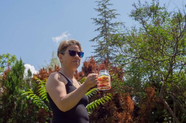 Genç kadın, bahçelerinde pilates ya da yoga yaptıktan sonra detoks içeceklerinin keyfini çıkarıyor..