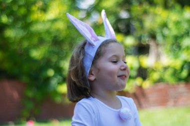 Tavşan kostümlü küçük kız evinin bahçesinde piknik yapıyor..