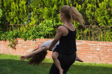 Genç kadın bahçede kucağında küçük kızıyla dans ediyor. Seçici Odaklanma. film resmi.