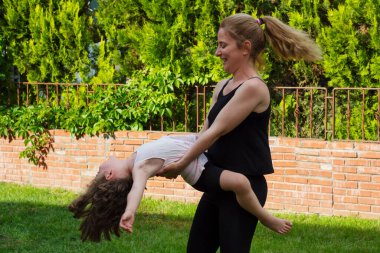 Genç kadın bahçede kucağında küçük kızıyla dans ediyor. Seçici Odaklanma. film resmi.