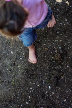 Küçük kız evlerinin bahçesinde yerde yalınayak yürüyor. Seçici Odaklanma Kızı