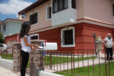 Evlerinin ön bahçesinde eski moda posta kutusunu kontrol eden genç bir kadın. Seçici Odak Posta Kutusu.