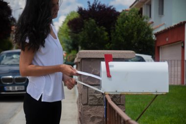 young woman checking old-fashioned mailbox at the front yard of their house. Selective Focus Mailbox. clipart