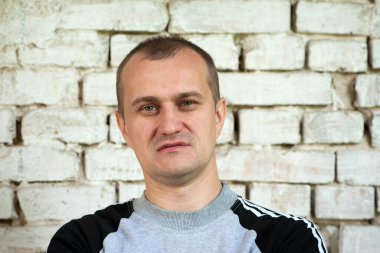 Genç Avrupalı. Erkek portresi. Adam tuğla duvarın önünde duruyor. fotoğraf, gülümseme, düşünceli, şaşırmış, kızgın, duygular, duygular. Açık tenli, sakallı. 30-40 yaşlarında bir adam. yakın plan